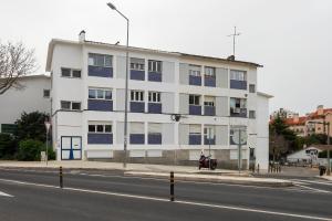 un bâtiment blanc avec des fenêtres bleues sur le côté d'une rue dans l'établissement Happy Holiday Cascais - Home, à Cascais