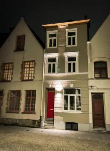 una casa blanca con una puerta roja en una calle en La Porte Rouge - The Red Door, en Oudenaarde