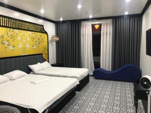 a bedroom with two beds and a blue chair at Song Kim Hotel in Hai Phong