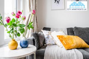 a living room with a couch and a table with vases at Charming 1 Bed Apt in Kensington - Free London Tour Included By City Apartments UK Short Lets Serviced Accommodation in London