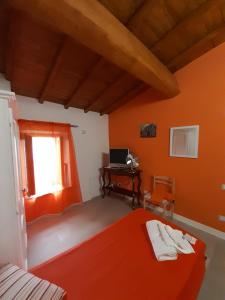 1 dormitorio con paredes de color naranja, 1 cama y escritorio en B&B Il Grifo, en Bomarzo