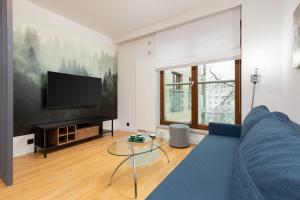 a living room with a blue couch and a flat screen tv at Park Arkadia Apartment with Parking Mokotów by Renters in Warsaw
