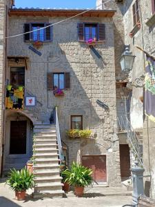 un edificio in pietra con scale, finestre e piante di B&B Il Grifo a Bomarzo