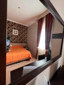 a bedroom with an orange bed and a window at Hotel Hermitage in Qualiano