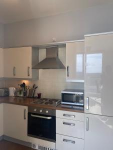 uma cozinha com armários brancos e um forno com placa de fogão em Apartment 7 em Milton Keynes