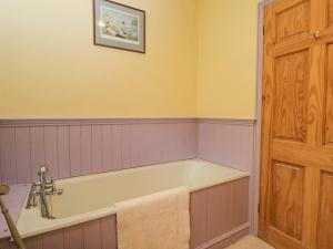 eine Badewanne in einem Badezimmer mit einem Bild an der Wand in der Unterkunft Field Cottage in Shepton Mallet + 19 Fotos