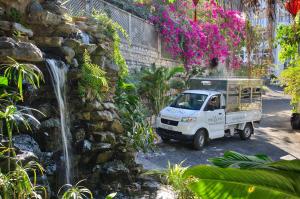 a white truck parked in front of a waterfall at The Wind Boutique Resort in Vung Tau