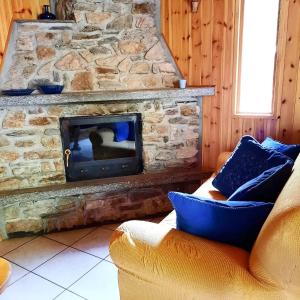 - un salon avec une cheminée en pierre et un canapé dans l'établissement Villetta Arcobaleno - Your Mountain Holiday, à Casargo