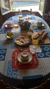 una mesa con platos y utensilios sobre un mantel azul en la maison blanche en Ustou