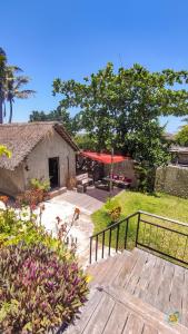 a wooden deck with a house and a tree at Kitesurf Tofo House in Praia do Tofo