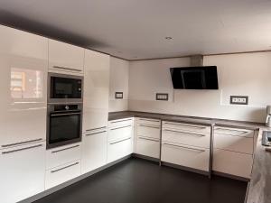 a kitchen with white cabinets and a tv on the wall at Dill Apartments Gadenstedt in Ilsede