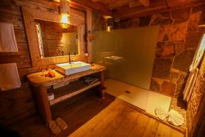 Baño en una cabaña de madera con lavabo y espejo en Hotel Xaluca Spa Aguelmame Sidi Ali, 