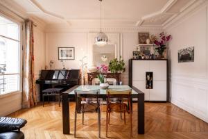 a dining room with a table and chairs and a piano at Veeve - Vivid, Vivace in Paris