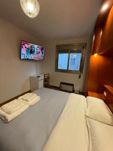 a bedroom with a large white bed with a flat screen tv at Habitación cómoda en Barcelona in Esplugues de Llobregat
