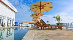 una piscina con bancos y sombrillas junto a un edificio en Gili Beachfront Suites, en Gili Trawangan