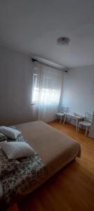 Schlafzimmer mit einem Bett, einem Tisch und einem Fenster in der Unterkunft Apartman Alenka in Tkon