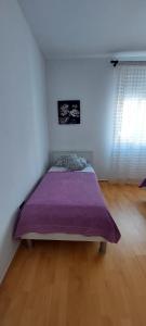 a bedroom with a bed with a purple blanket at Apartman Alenka in Tkon