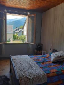 um quarto com uma cama e uma grande janela em la maison blanche em Ustou