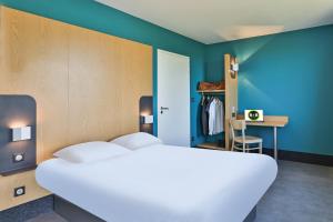 um quarto com uma cama branca e uma parede azul em B&B HOTEL La Roche-sur-Yon em Mouilleron-le-Captif