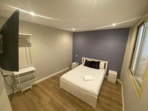 Schlafzimmer mit einem weißen Bett und einem TV in der Unterkunft Apartamentos Sol Madrid in Madrid