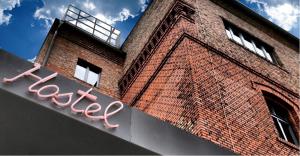 a brick building with a neon sign on it at Pfefferbett Hostel in Berlin