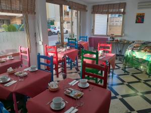 a restaurant with red tables and colorful chairs at Hotel Clibomar Jamaica in Gandía
