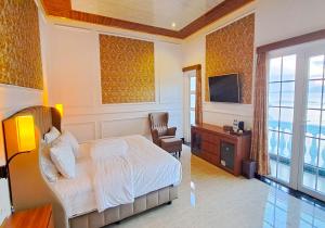 a bedroom with a bed and a chair and a television at Gili Beachfront Suites in Gili Trawangan
