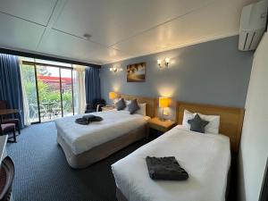 a hotel room with two beds and a balcony at Statesman Motor Inn in Ararat