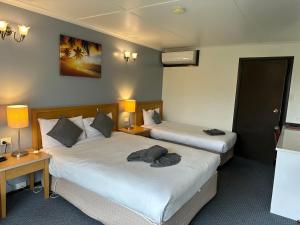 2 Betten in einem Hotelzimmer mit 2 Lampen in der Unterkunft Statesman Motor Inn in Ararat