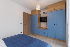 a bedroom with a blue bed and a tv at Casa Iringo Apartman By BLTN Balatonföldvár in Balatonföldvár