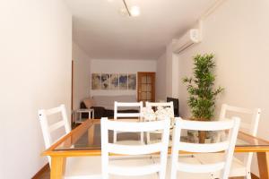 a dining room with a glass table and white chairs at INNOUTHOME Apartamento Eixample Barcelona in Barcelona