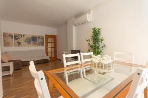 バルセロナにあるINNOUTHOME Apartamento Eixample Barcelonaのリビングルーム(ガラステーブル、白い椅子付)