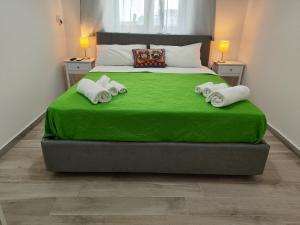 duże łóżko z zieloną pościelą i ręcznikami w obiekcie B&B CESARE'S Guests w mieście Aci Trezza