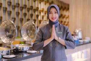 a woman in a hijab is holding her hands up at KHAS Semarang Hotel in Semarang