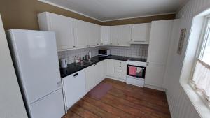 a kitchen with white cabinets and a wooden floor at Cozy Apartment between sea and mountains in Mefjordvær