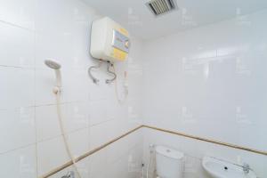 a bathroom with a toilet and a phone on the wall at RedLiving Apartemen Vivo Yogyakarta - WM Property in Yogyakarta