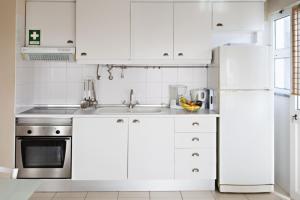een witte keuken met een wastafel en een koelkast bij Blue Sky Apartment in Faro