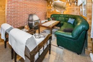 sala de estar con sofá de cuero verde y TV en Metsämökki, en Kelkala