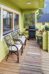 une terrasse couverte avec des chaises et un grill dans une maison jaune dans l'établissement Metsämökki, à Kelkala