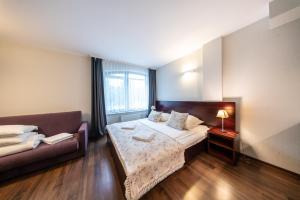 Habitación de hotel con cama y sofá en Apartamenty i pokoje ,,Leśne" en Jastarnia
