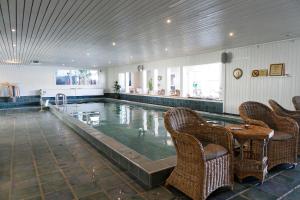 a swimming pool with chairs and a table in a building at Orbaden Spa & Resort in Vallsta