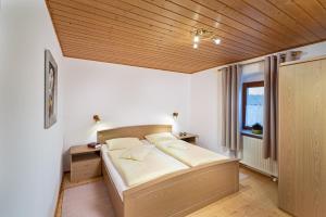 sypialnia z łóżkiem i drewnianym sufitem w obiekcie Ferienhof Weishäupl w mieście Untergriesbach