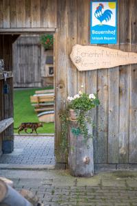 a sign on a wooden building with a pot of flowers at Ferienhof Weishäupl in Untergriesbach