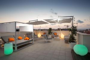 eine Dachterrasse mit Tischen, Stühlen und einem Sonnenschirm in der Unterkunft Giada Luxury in Terrasini