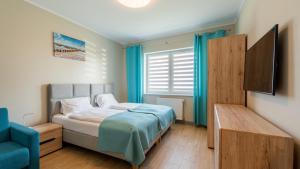 - une chambre avec un lit et une chaise bleue dans l'établissement Apartamenty Sun & Snow Osiedle Północne, à Darłówko