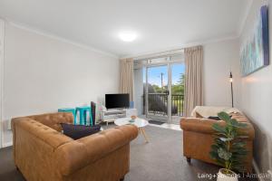 a living room with two couches and a tv at TC GARDENS 11 in Armidale