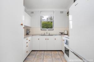 a white kitchen with a sink and a window at TC GARDENS 11 in Armidale