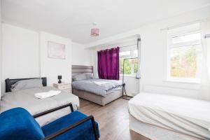 a bedroom with two beds and a couch and a window at HeadsonBed- Croydon 4Bedrooms with Parking for the Larger groups in Hackbridge