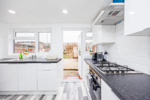 a kitchen with white cabinets and a stove top oven at HeadsonBed- Croydon 4Bedrooms with Parking for the Larger groups in Hackbridge