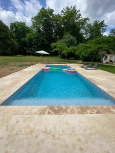 ein leerer Pool mit Sonnenschirm im Hof in der Unterkunft la Chartreuse du Domaine de la Graulet in Bergerac